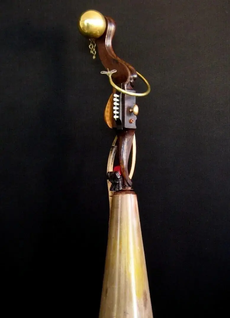 Wooden sculpture with brass and red accents.