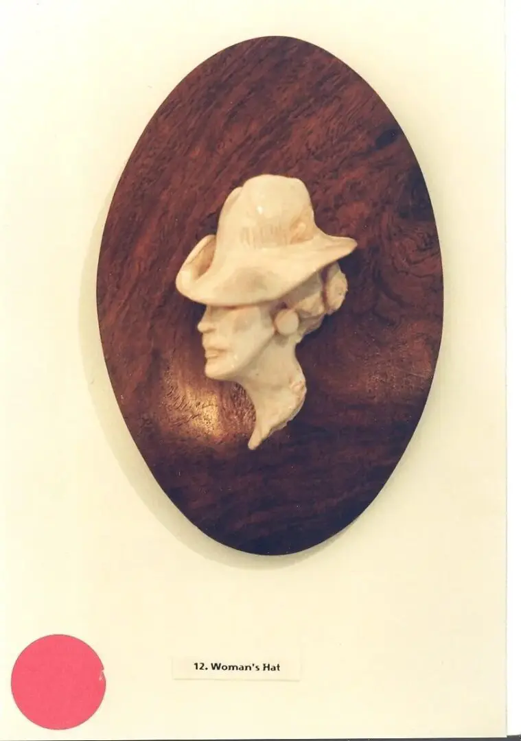 Carved woman's profile with hat sculpture.