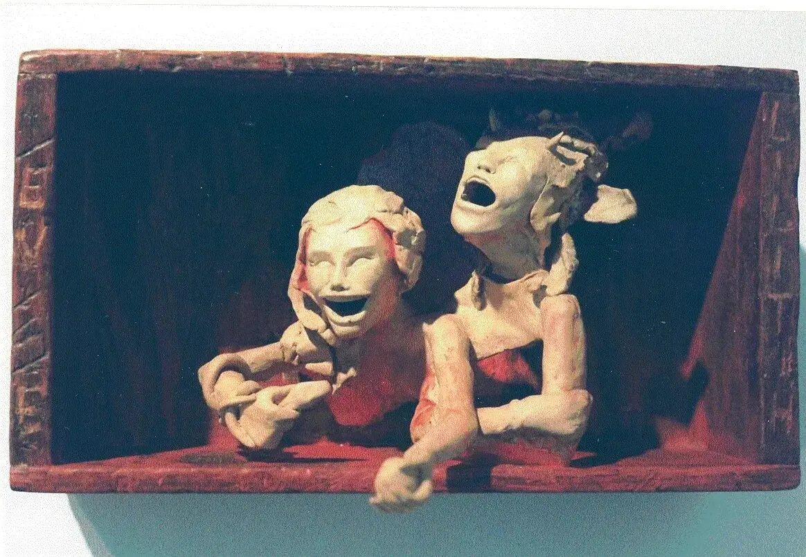 Two expressive puppets in a wooden box.