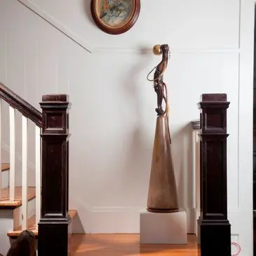 Sculpture on pedestal between staircase railings.