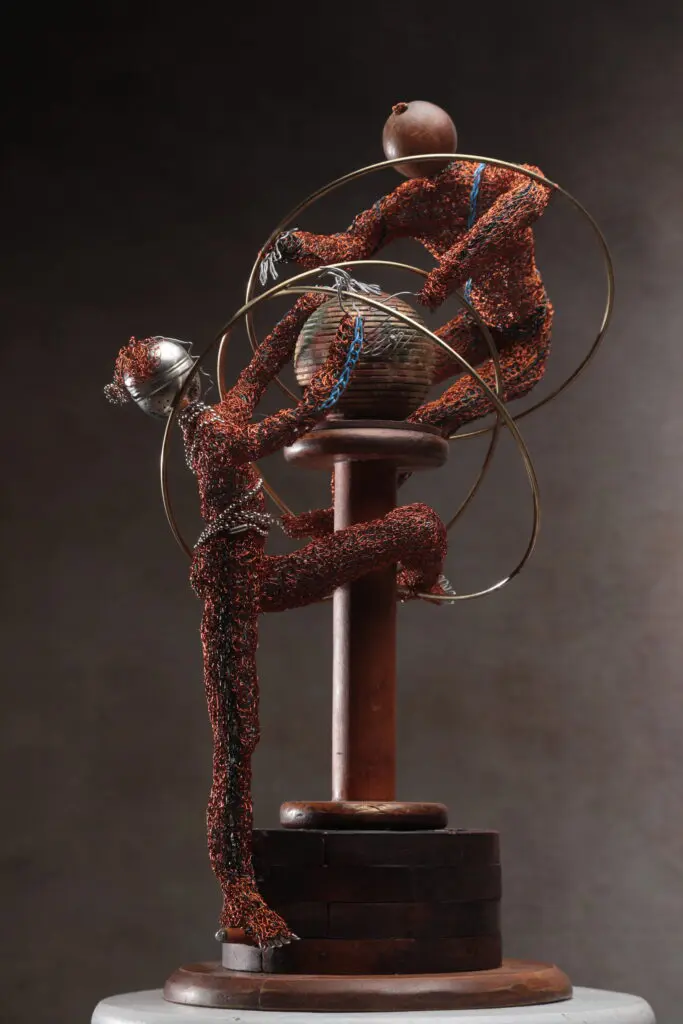 Abstract sculpture of a seated figure with tangled wires.